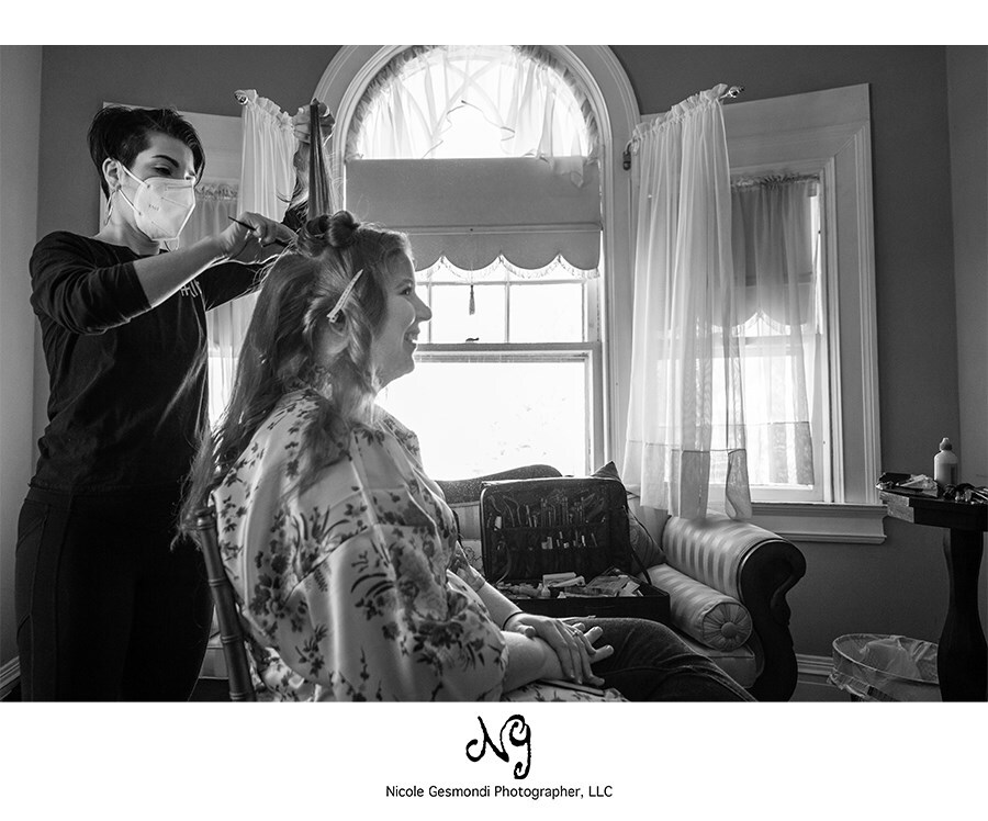 black and white photo of a bride getting her hair done on wedding day