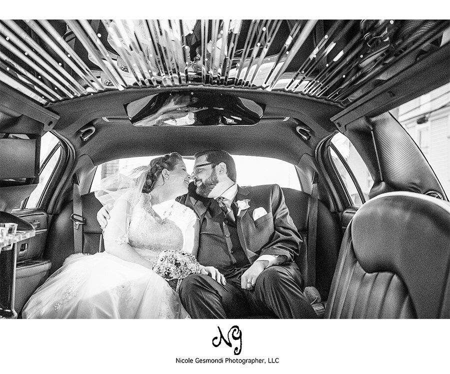 black and white photo of bride and groom kissing in limo