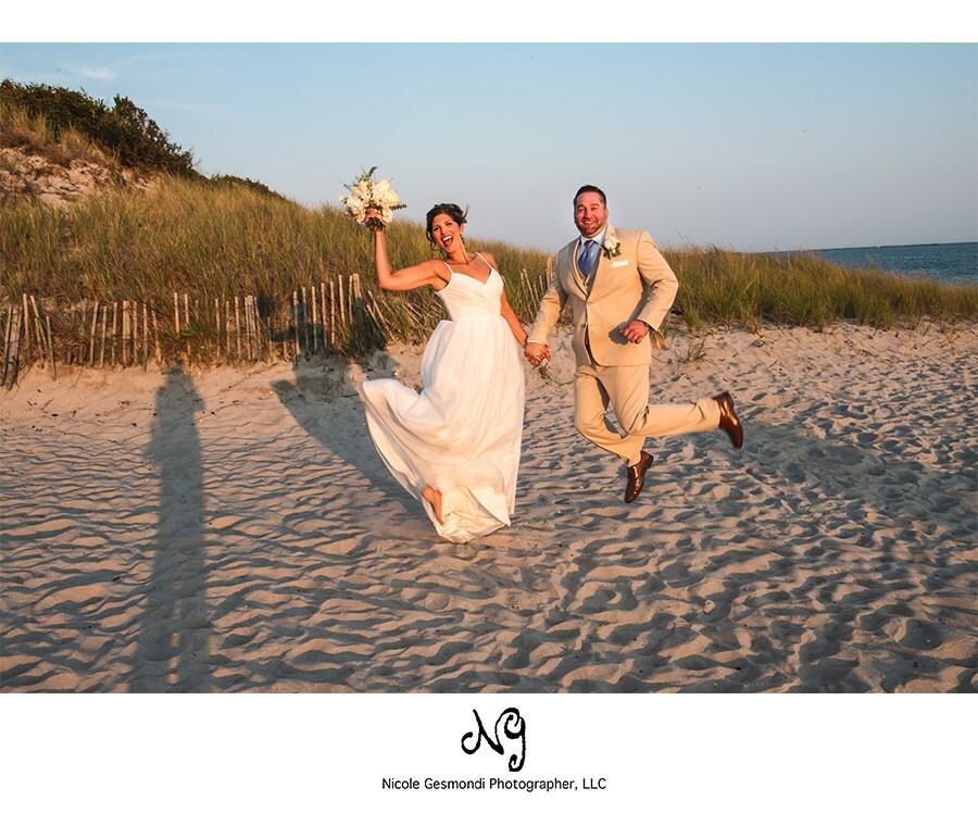 bride and groom jumping in the air at their beach wedding